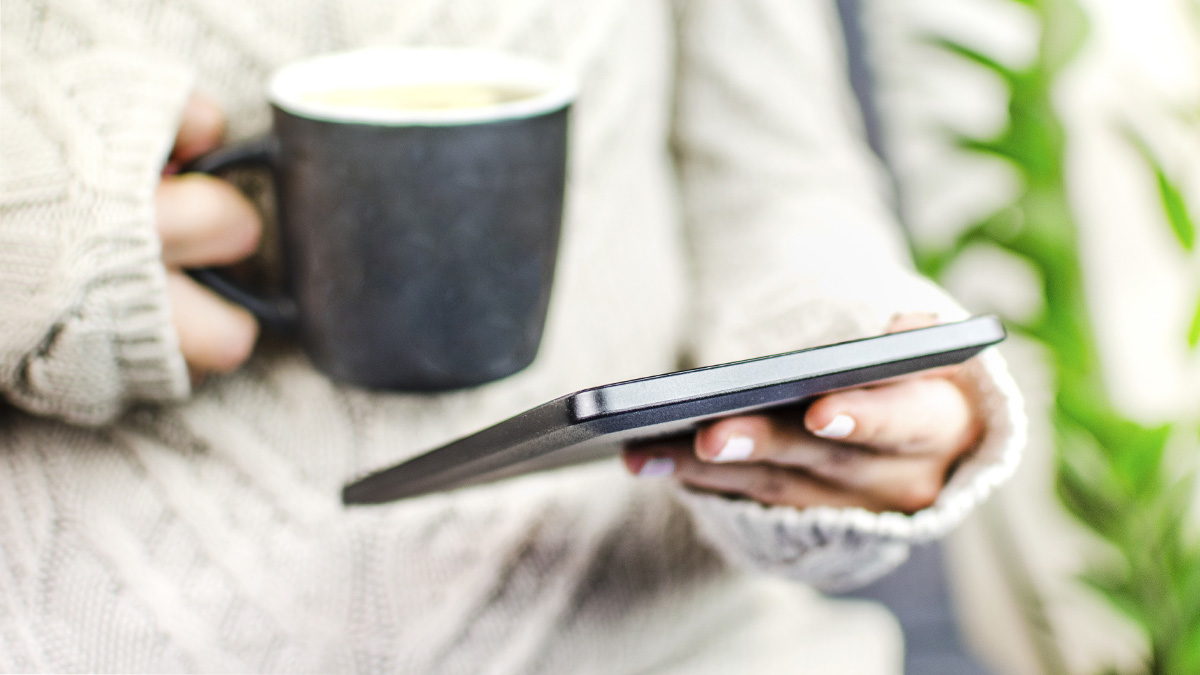 Stock photo of a person reading an ebook with a coffee
